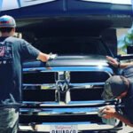 98afcd_fc56f522324342bcb4a31c3df399d02d~mv2 Two people polishing a black truck front