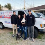 UNITED FAMILY PHOTO A group of four people with two dogs by a van.