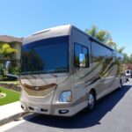 20220621_123153 Luxury RV parked in a sunny residential area.