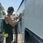 20220822_103920 Person cleaning an RV under sunny skies.