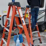 20230213_094520 Person cleaning RV using ladders and tools.