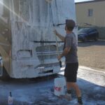 20230318_082927 Person washing a vehicle with soap and water.