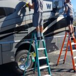 20230318_100619 Two individuals cleaning the side of an RV.