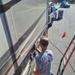 20250410_092002 Man cleaning an RV in bright sunlight.