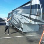 VideoCapture_20230118-155531 Person washing a large RV under blue sky.